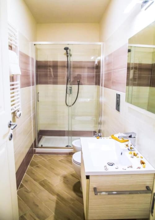 Baño moderno en Borgo Angioino con ducha a ras de suelo, lavamanos blanco, inodoro y suelos de baldosa en espiga en Nápoles