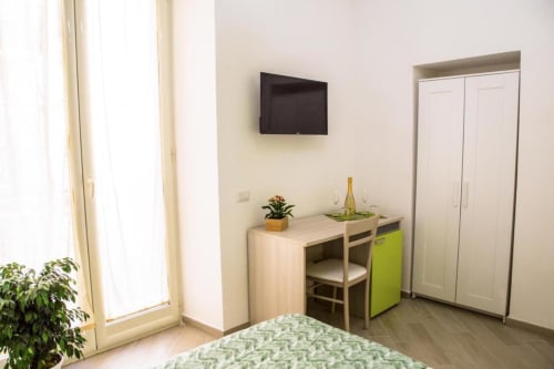 Camera moderna del Borgo Angioino BnB a Napoli con scrivania, TV, armadio e biancheria verde