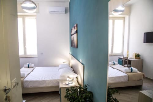 Camera twin al Borgo Angioino B&B a Napoli con parete d'accento turchese, illuminazione moderna e arredi contemporanei