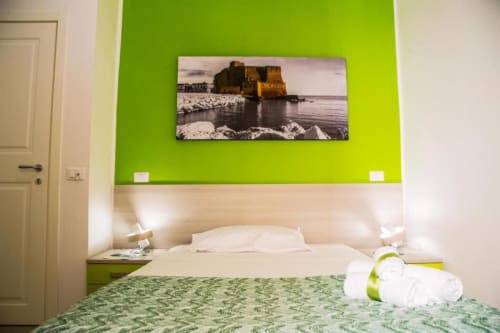 Camera moderna verde e bianca a Borgo Angioino B&B a Napoli con letto, fotografia murale di castello costiero e arredamento contemporaneo