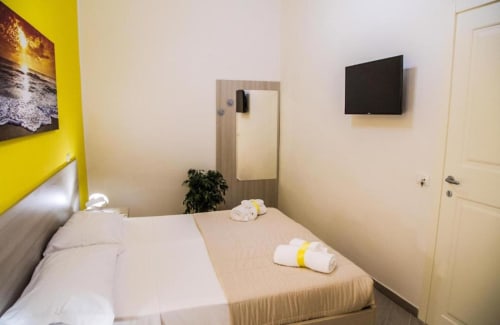 Accogliente camera in toni giallo e beige presso Borgo Angioino B&B Napoli, con TV e servizi moderni