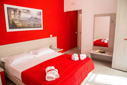 Camera moderna rosso e bianco presso il Borgo Angioino BnB a Napoli con letto, specchio e opere incorniciate