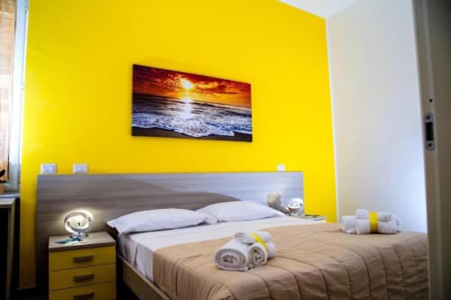Dormitorio amarillo brillante en Borgo Angioino en Nápoles con cama, obra de puesta de sol y comodidades modernas