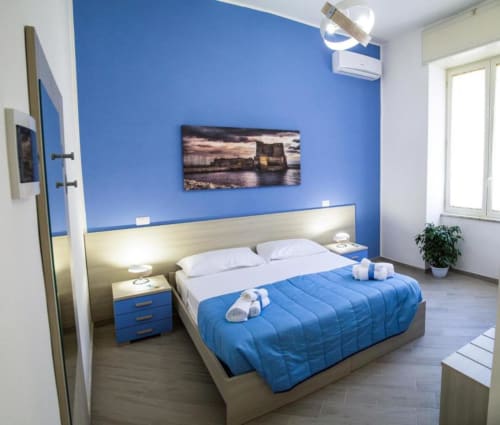 Dormitorio moderno azul y crema en Borgo Angioino BnB en Nápoles con vistas a la ciudad, cama doble y mobiliario contemporáneo