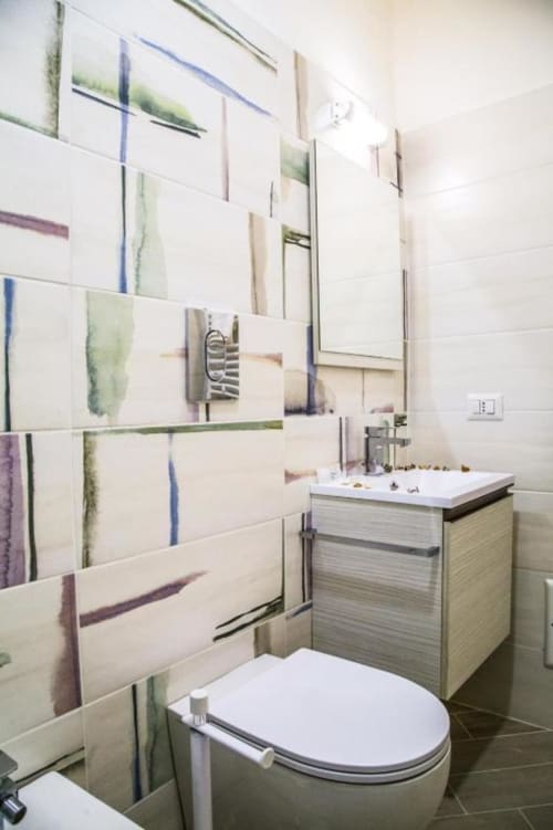 Baño moderno en Borgo Angioino B&B en Nápoles con pared de azulejos artísticos, lavabo blanco, inodoro y área de ducha