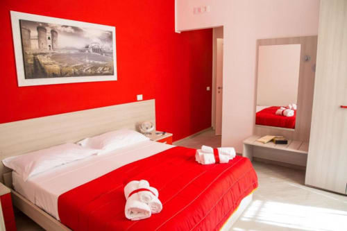 Dormitorio moderno rojo y blanco en Borgo Angioino B&B en Nápoles con cama de madera, cuadros enmarcados y vista al patio interior