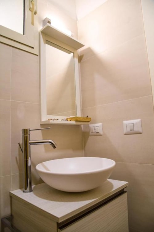 Baño moderno en B&B de Nápoles con lavabo blanco, grifo cromado, espejo y azulejos beige