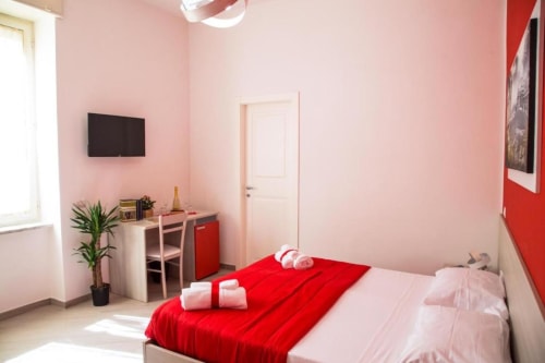 Camera moderna a Borgo Angioino B&B a Napoli con biancheria rossa e rosa, TV, scrivania e vista sulla corte interna