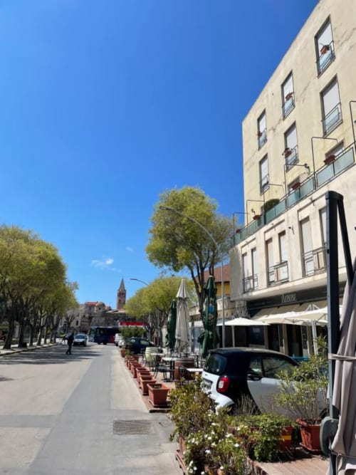 Ingresso dell'hotel Catalogna10 Rooms e Loft ad Alghero con viale alberato e zona esterna