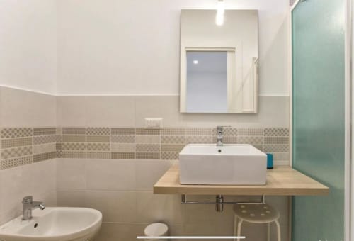 Modern bathroom at Catalogna10 Rooms in Alghero with white vessel sink, patterned tile accents, and mirror