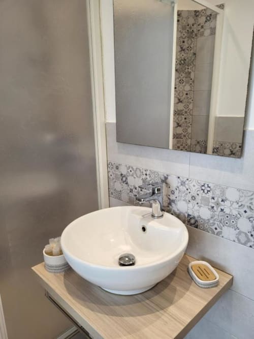 Modern bathroom vanity at Catalogna10 Rooms e Loft in Alghero with round white sink and decorative tile backsplash