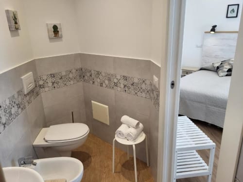 Modern bathroom with toilet, sink, and beige tiled walls at Catalogna10 hotel in Alghero, Italy