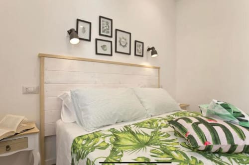 Bright double bedroom at Catalogna10 Rooms, Alghero with botanical bedding, wooden headboard and framed leaf artwork