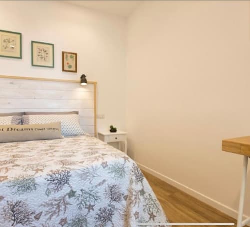 Cozy double room at Catalogna10 in Alghero with white wood headboard, floral bedding, botanical wall art, and wooden