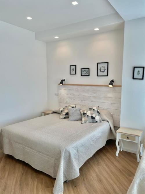Modern bedroom at Catalogna10 in Alghero with bed, wooden headboard, framed artwork, and neutral decor