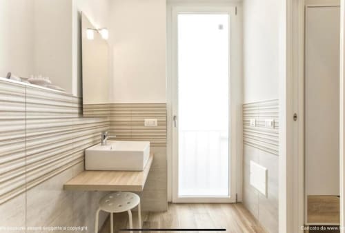 Modern bathroom at Catalogna10 Rooms e Loft in Alghero with striped tile, vessel sink, and natural light