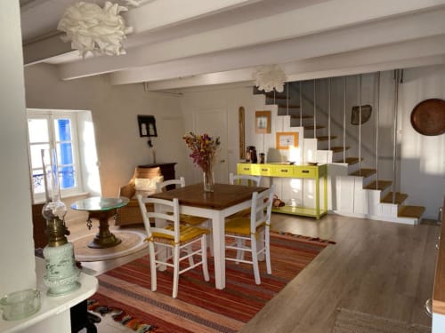 Intérieur d'appartement lumineux avec table à manger, rangements jaunes, escalier blanc et vue sur la mer à Locations
