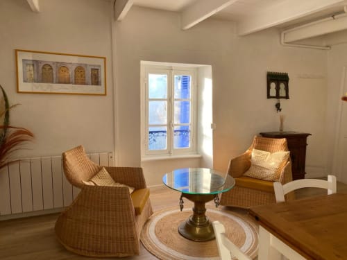 Salon côtier lumineux avec fauteuils en rotin, table ronde en verre et vue sur mer à Locmaria, Belle Île-en-Mer