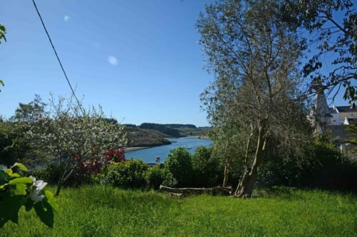 Vue sur le jardin dominant l'eau azurée et les collines onduleuses du gîte Locmaria à Belle Île en Mer