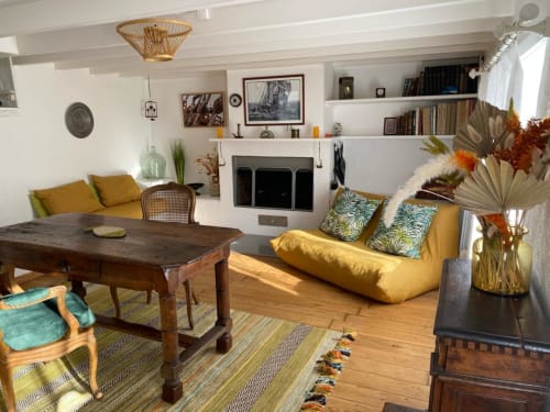 Séjour douillet aux Locations Loc'Maria, Belle Île en Mer, avec canapé jaune moutarde, mobilier bois, cheminée