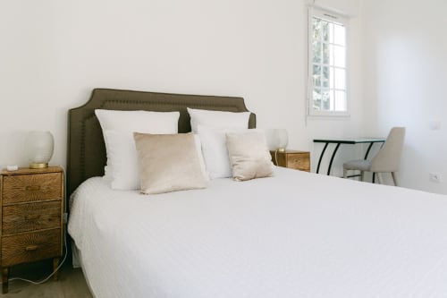 Helles Schlafzimmer mit olivefarbenem gepolstertem Kopfteil, weißer Bettwäsche und Holznachttisch im Domaine de Bize in Mirepoix
