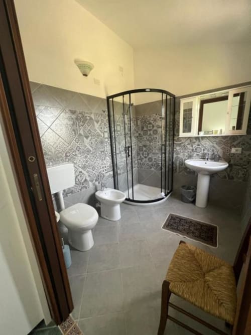 Bagno moderno presso l'Agriturismo Su Barraccu a Loceri con doccia curva, doppio lavabo e pareti in piastrelle decorate