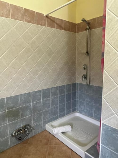 Modern bathroom shower stall with diagonal tile pattern and rainfall showerhead at Agriturismo Su Barraccu, Loceri