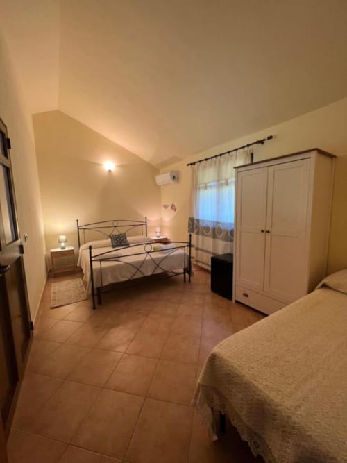 Spacious bedroom at Agriturismo Su Barraccu with twin beds, wardrobe, and garden view in Loceri