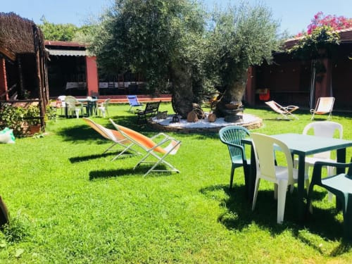 Agriturismo Su Barraccu garden courtyard with loungers, dining table, firepit, and rustic buildings in Loceri