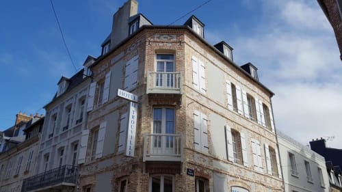 Hotel Le Trouville, a brick facade hotel in Trouville sur Mer with mansard roof and white shutters