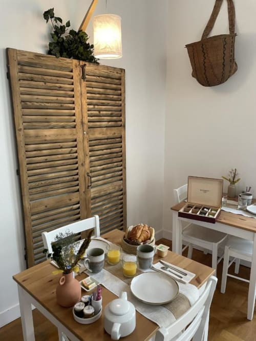 Breakfast setup at Hotel Le Trouville in Trouville sur Mer with wooden louvered screen, fresh pastries, and morning beverages