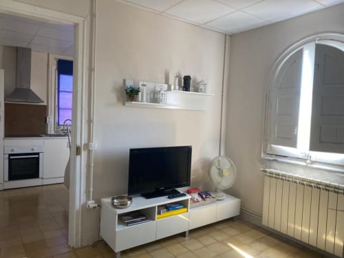 Sala de estar moderna en Cuartel del Montsant con televisor, estanterías blancas y vistas a las montañas desde ventana arqueada