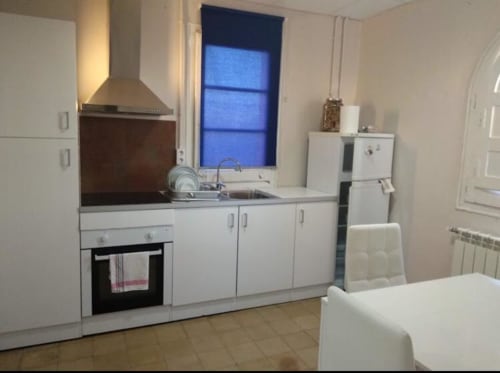 Moderna cocina blanca con electrodomésticos de acero inoxidable en el apartamento Cuartel del Montsant en La Granadella