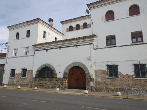Edificio histórico de piedra encalada Cuartel del Montsant en La Granadella con puerta de arco y vistas a las montañas