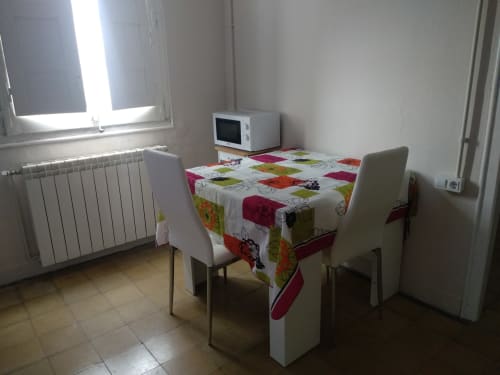 Cocina-comedor luminosa en Cuartel del Montsant con mantel colorido, dos sillas, microondas, radiador y