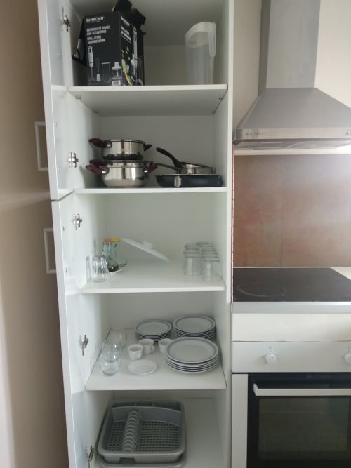 Armario de cocina abierto con utensilios, platos y vasos en el apartamento Cuartel del Montsant en La Granadella