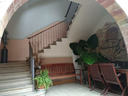 Entrada del apartamento en Cuartel del Montsant con escalera, bancos de madera, plantas en maceta y arco de ladrillo en La Granadella.
