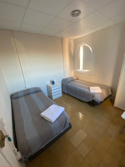 Habitación doble en apartamento Cuartel del Montsant en La Granadella con dos camas, cómoda blanca y vistas a la montaña