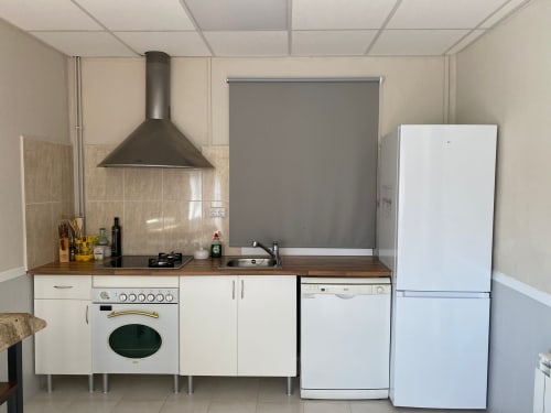 Cocina moderna en Cuartel del Montsant con electrodomésticos blancos, campana oscura y azulejos de protección