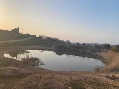 Sereno paisaje fluvial en el Cuartel del Montsant de La Granadella, España, con ruinas en la ladera y vistas montañosas envueltas en niebla