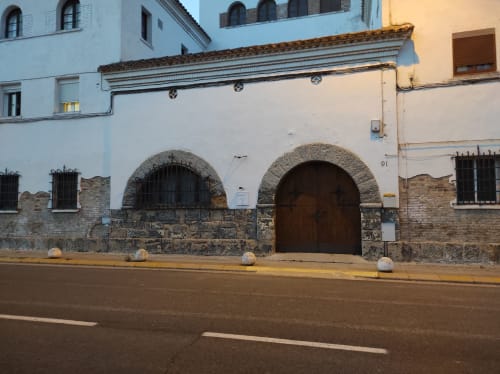 Fachada de piedra histórica del hotel Cuartel del Montsant en La Granadella con entrada abovedada y muros encalados