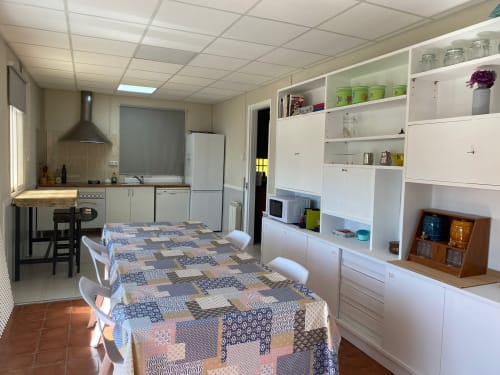 Cocina y comedor abiertos en apartamento Cuartel del Montsant en La Granadella con muebles blancos y diseño estampado