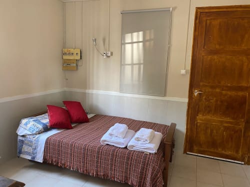 Dormitorio del apartamento Cuartel del Montsant en La Granadella con cama, almohadas rojas, toallas y ventana con vistas a la montaña