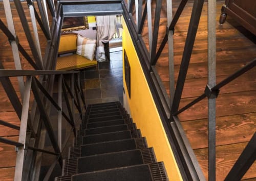 Staircase leading up to Le Calle Apartment at Dimora i Manichei, Monforte d'Alba, with yellow railing and wood flooring.