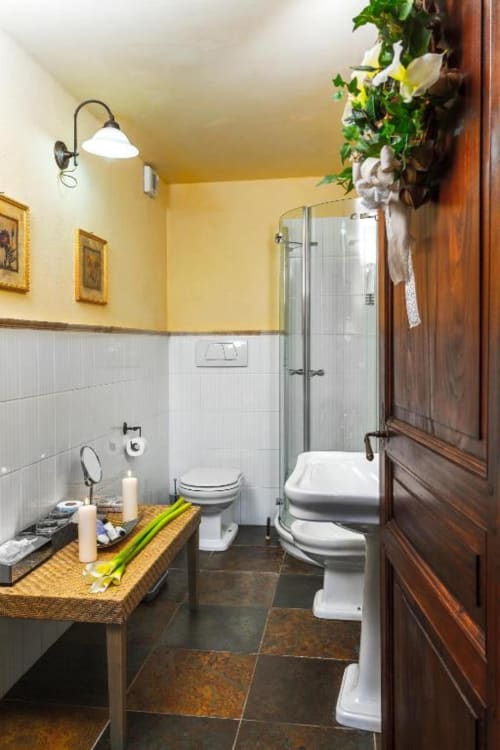 Elegant bathroom at Dimora i Manichei with yellow walls, white subway tiles, dark slate flooring, and wooden door in Monforte
