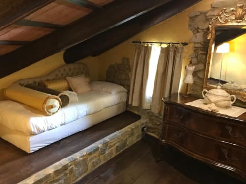 Camera da letto dell'appartamento Orchidea a Dimora i Manichei con letto imbottito, camino, cassettone, specchio e illuminazione calda