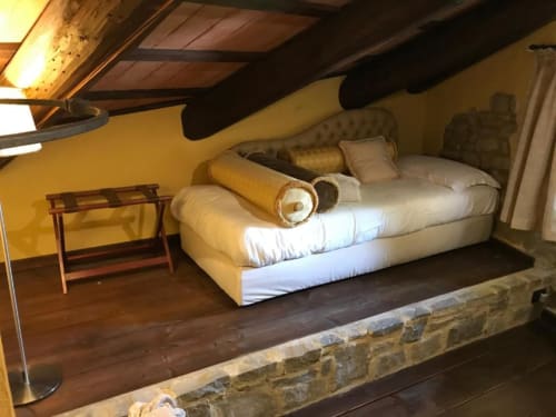 Camera da letto accogliente in mansarda a Dimora i Manichei con travi a vista, letto bianco e arredi in legno a Monforte d'Alba