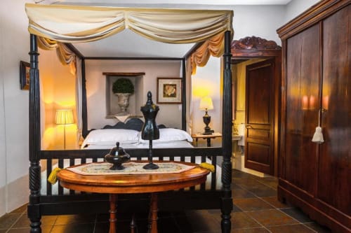 Elegant four-poster bed with gold drapes in Apartment Le Rose at Dimora i Manichei, Monforte d'Alba, featuring dark wood