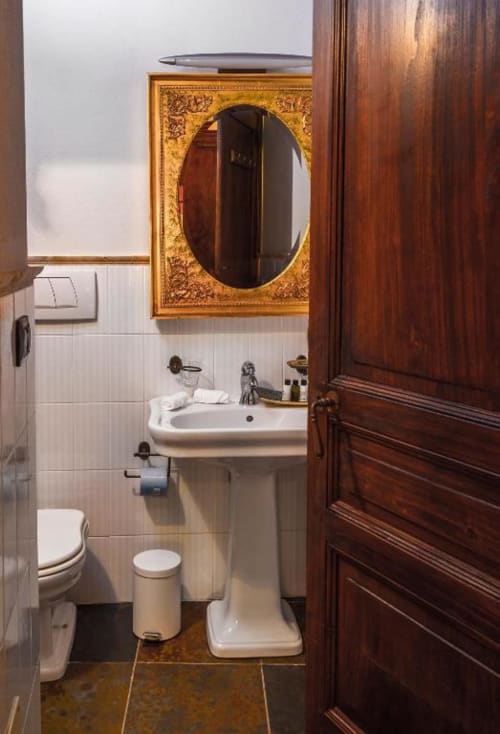 Elegant bathroom with pedestal sink, ornate gold-framed mirror, and traditional fixtures at Dimora i Manichei in Monforte