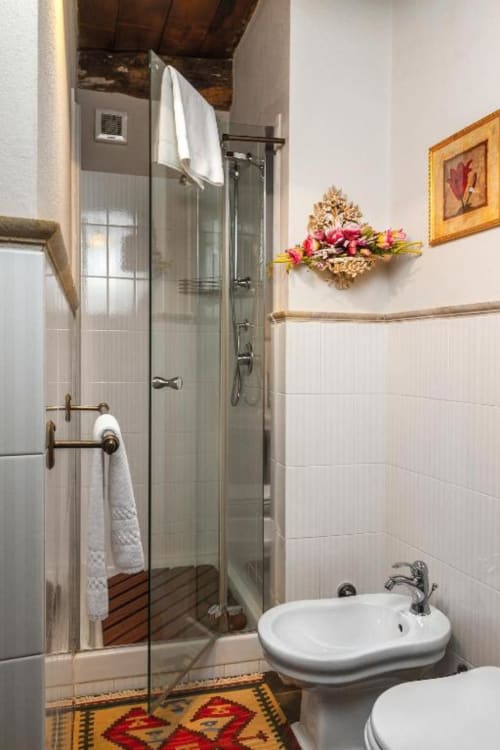 Modern bathroom with shower enclosure, white sink, and decorative floral arrangement at Dimora i Manichei, Monforte d'Alba